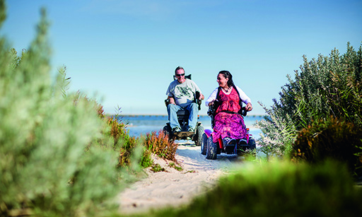 Adults in all-terrain wheelchairs on the beach
