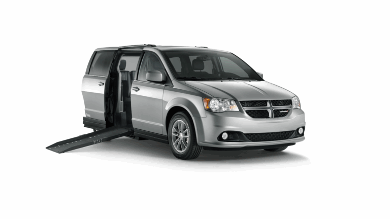 A silver minivan with its side sliding door open and a ramp extended to the ground, designed for accessible transportation and convenient driver’s side car transfers.