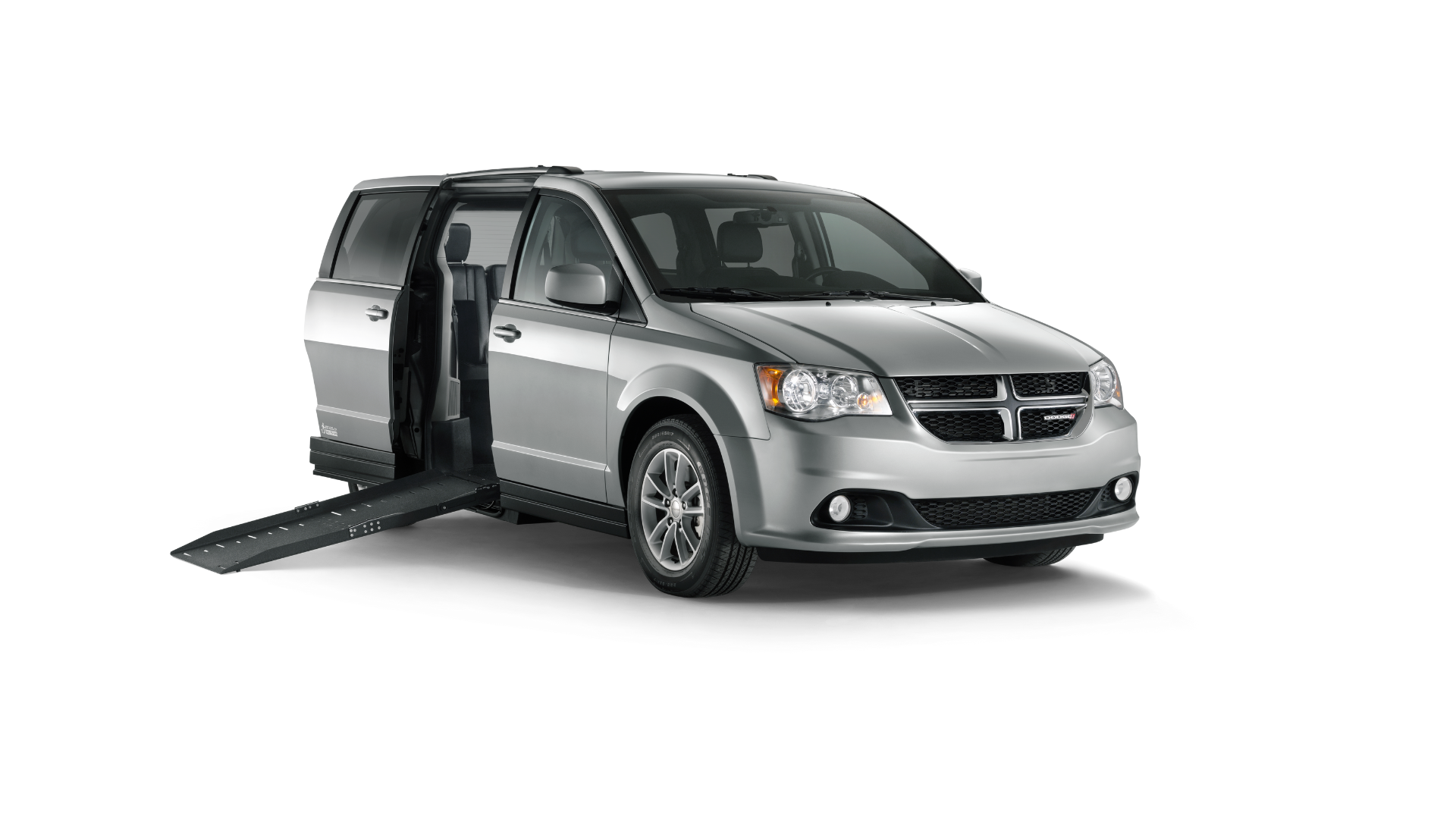 A silver minivan with its side sliding door open and a ramp extended to the ground, designed for accessible transportation and convenient driver’s side car transfers.
