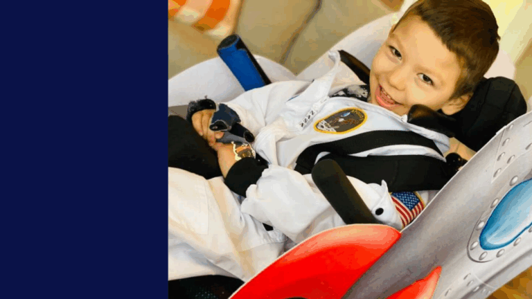 A young boy dressed in a white astronaut costume sits smiling in a car seat designed to look like a rocket ship. His hands are folded, and there is a patch with a space emblem on his outfit—this is part of Jacks Story.